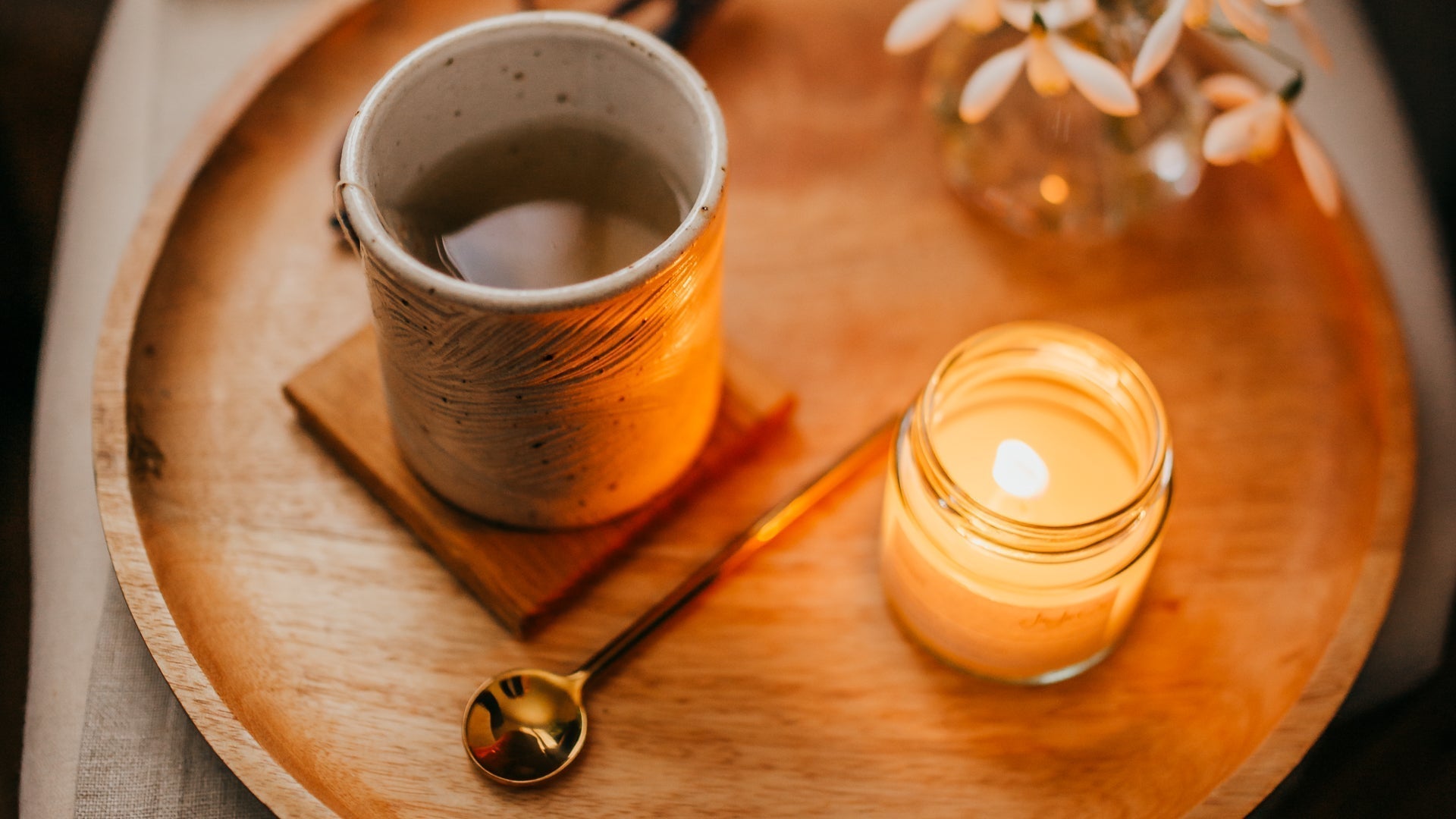 A softly glowing handmade pottery mug candle in a calm, atmospheric setting, creating a peaceful moment of reflection and warmth during a quiet evening.
