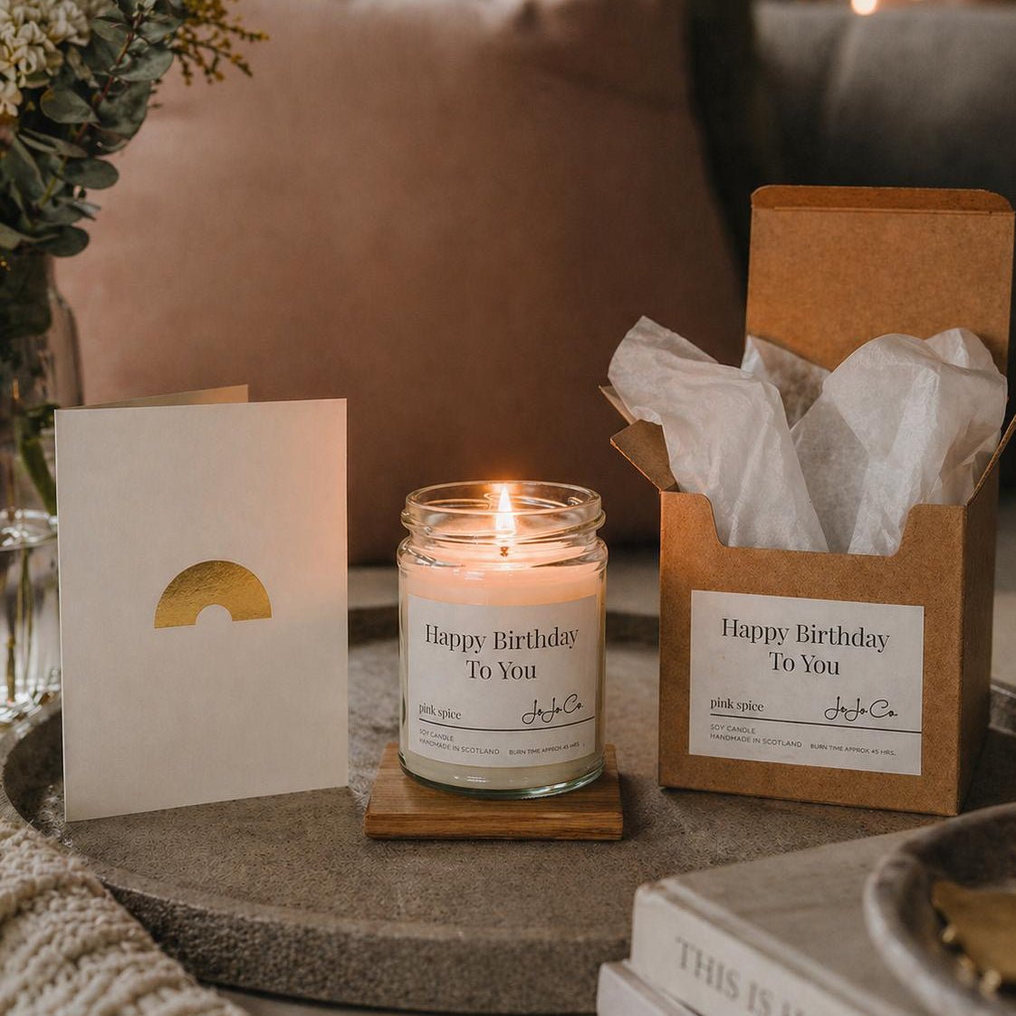 Candle with 'Happy Birthday To You' luxury candle, rainbow gold foil card and gift box on a table