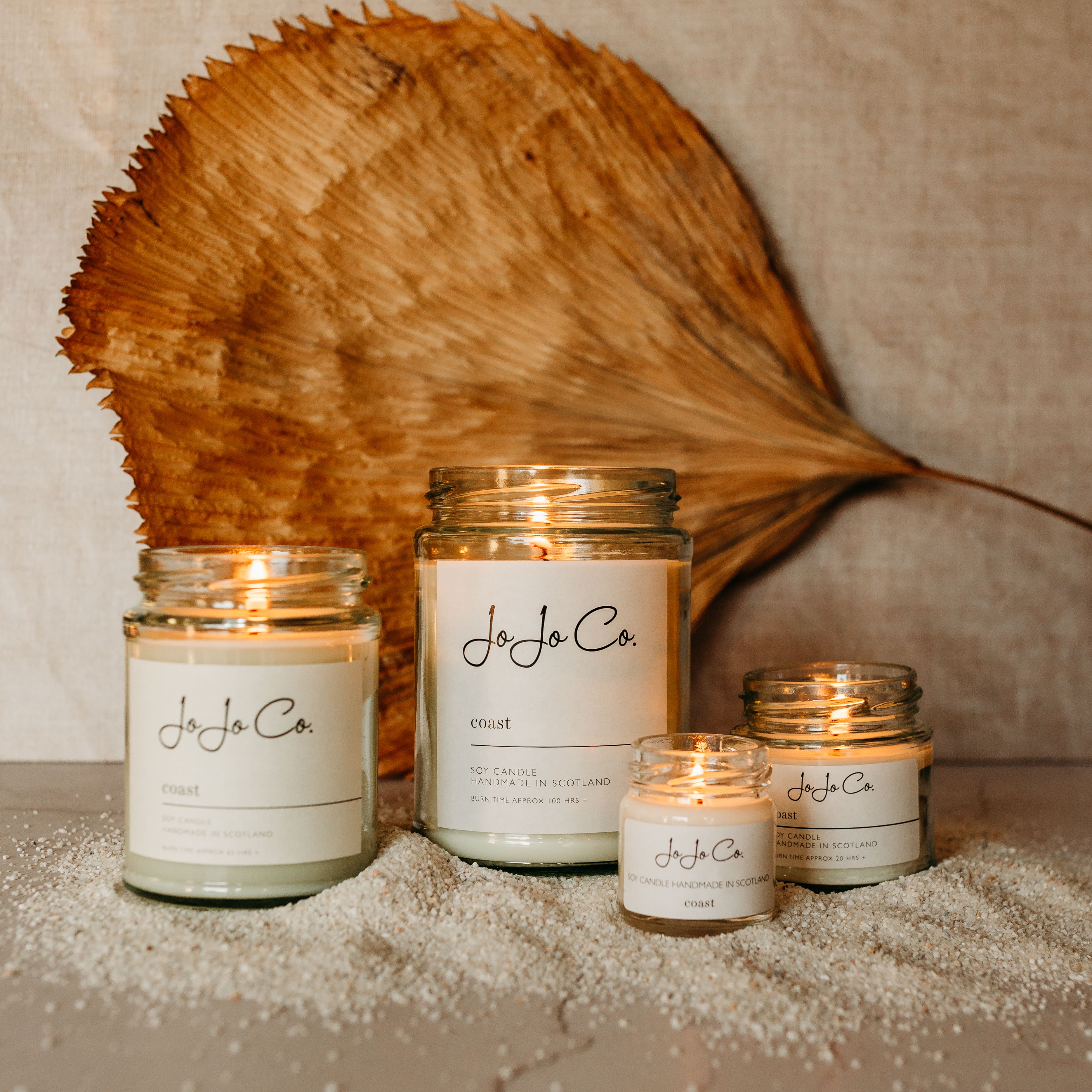 Group of different sized JoJo Co Coast Candles lit jars