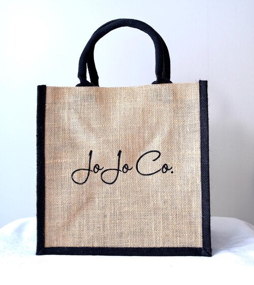 A natural coloured jute bag with black trimming and JoJo Co. logo