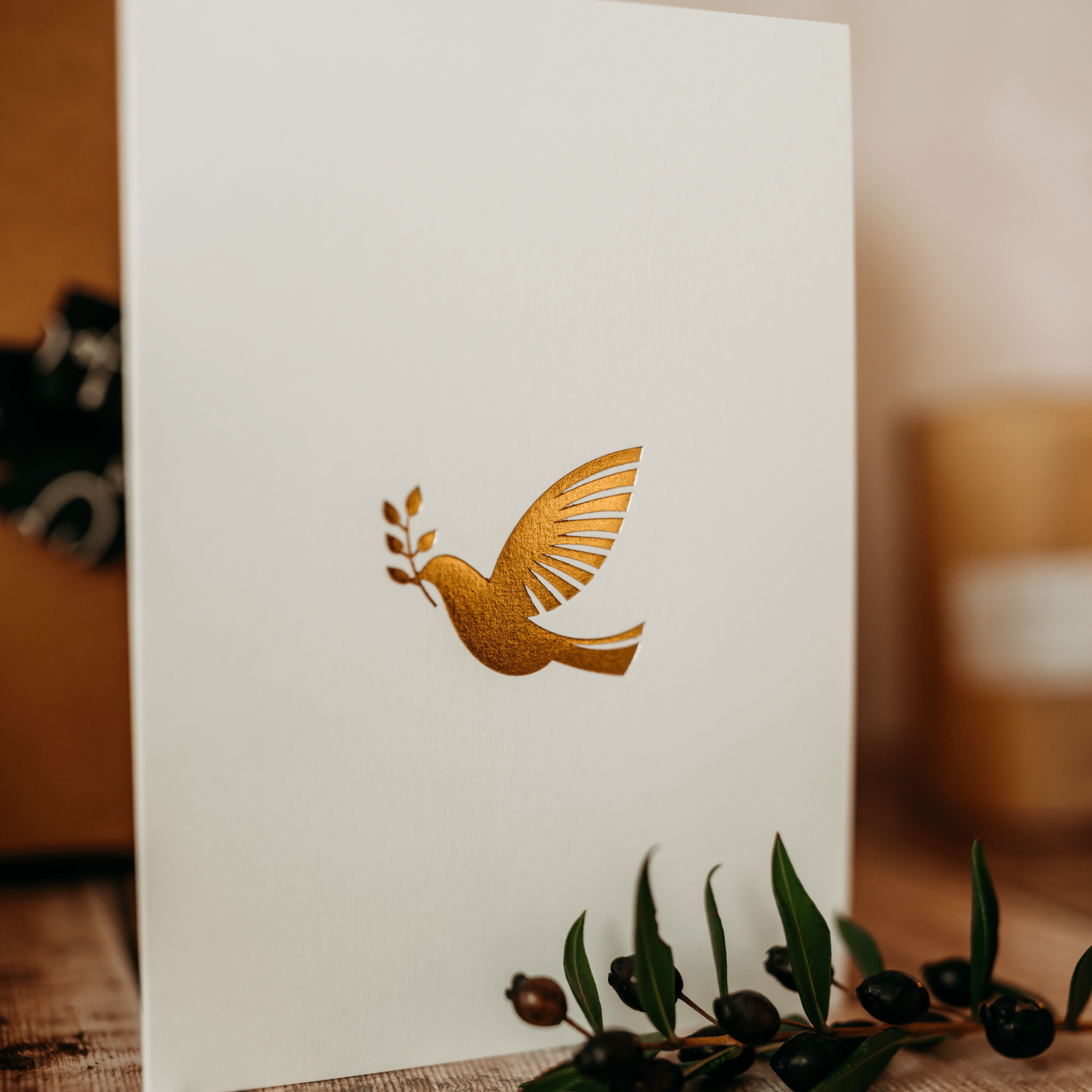 White card with gold dove design on a wooden surface, handwritten optional addition.