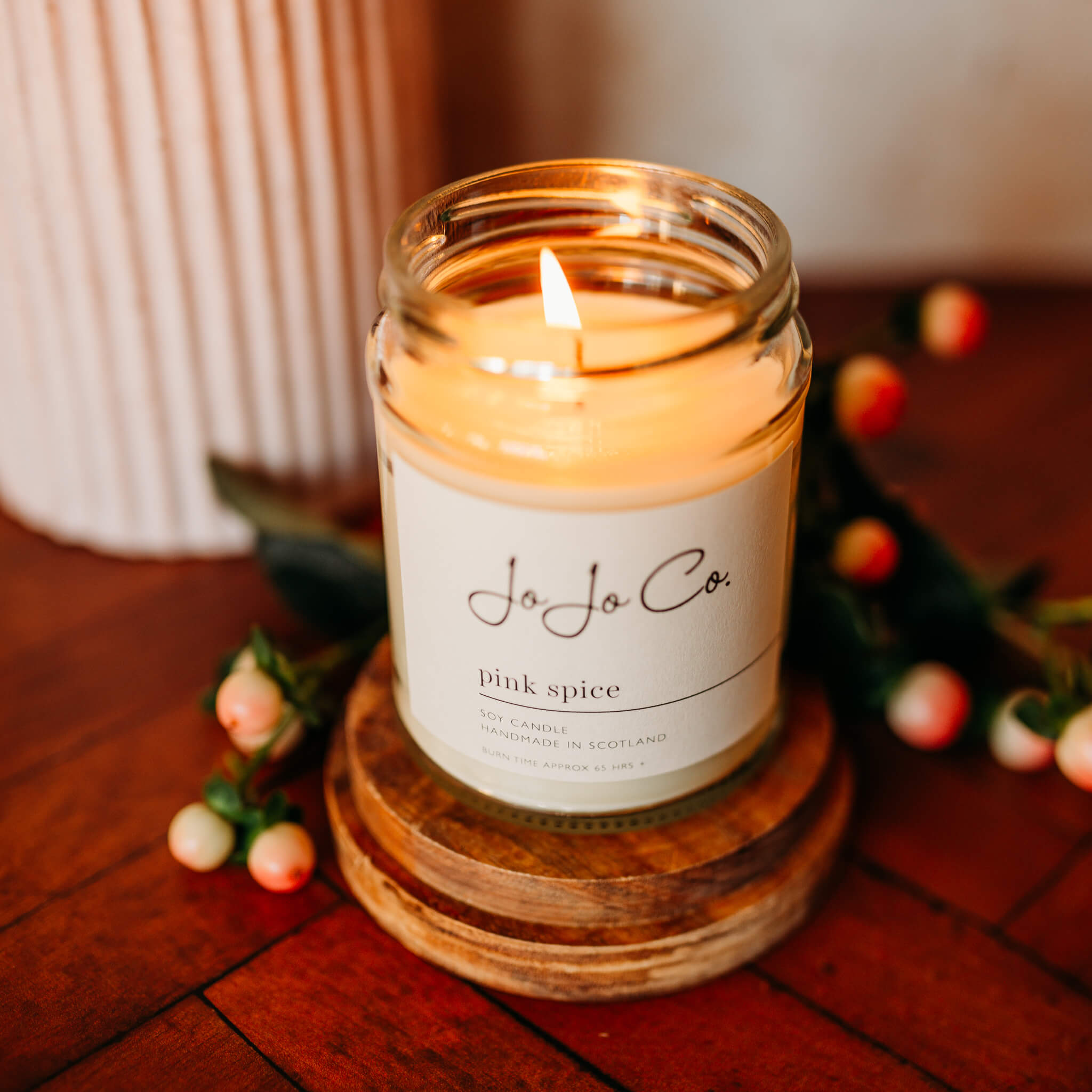 Lit Pink Spice candle on an oak candle base