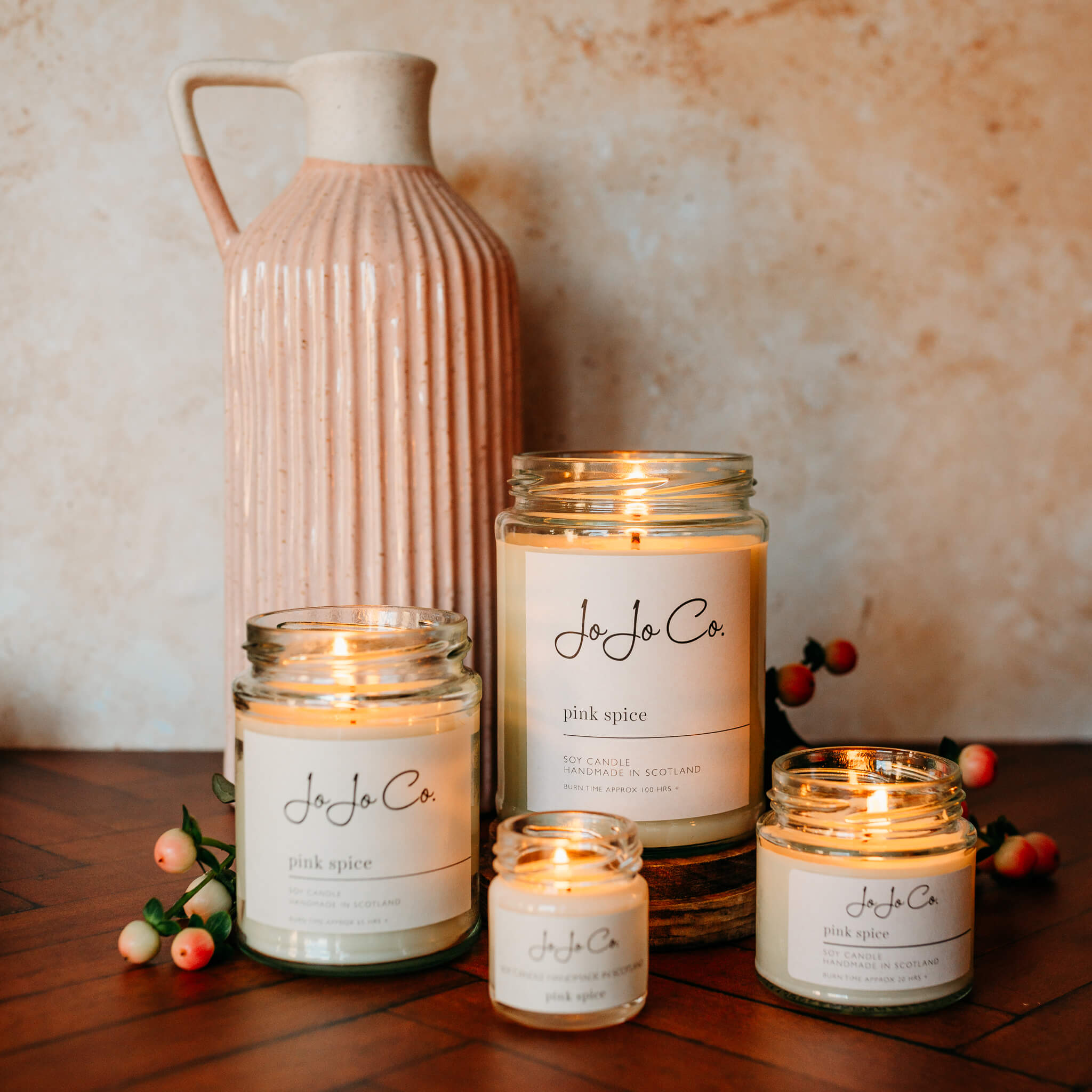 A group of lit JoJo Co Pink Spice candles in jars
