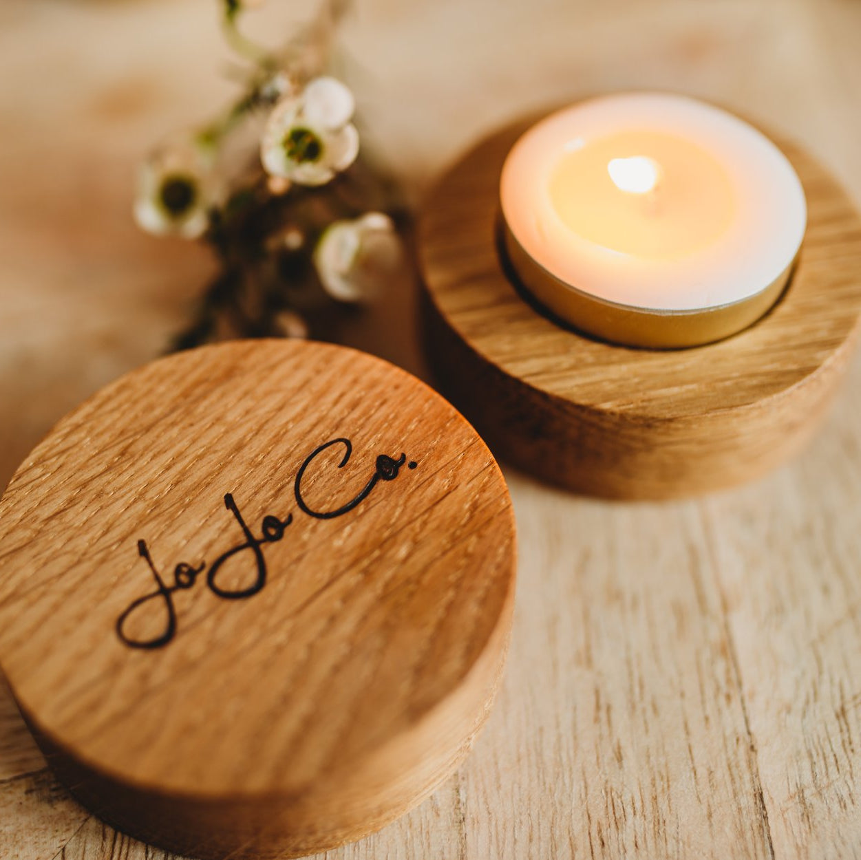 Two JoJo Co Scottish Oak tealight holders with lit soy wax tealight, hand-carved in Fife from sustainable Scottish Oak